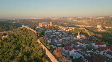 Akşam güneşinin altında ortaçağ duvarları olan bir kale kasabası. Tarihi mimari eski şehir manzaralı kırsal alanda duruyor. Antik binalar ve taş kale manzaralı şehir manzarası yaratıyor..