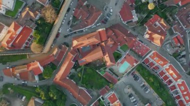 Akşam güneşinde şehrin en tepedeki kırmızı çatıları. Samimi şehir sokakları ve yerleşim alanları güzel şehir. Asfalt yolları olan kırmızı kiremitli binalar. Doğa ve mimari desenli kentsel düzen