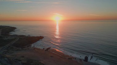 Güneşin doğuşu dalgalı deniz sahili hava manzarası. Karanlık ve dingin okyanus yüzeyinde altın şafak. Gün batımında ağır çekimde hareket eden huzurlu dalgalar. Meditasyon yapan sakin deniz manzarası 