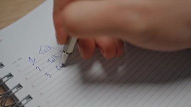 İş yerinde muhasebe defterini yazan eller, yakın plan. Tanımlanamayan adam yöneticisi ahşap masada yapılacaklar listesine not alıyor. Kimliği belirsiz işadamı ofiste yalnız çalışıyor. 