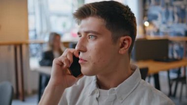 Ofiste oturan akıllı telefondan konuşan ciddi bir iş adamı. Modern iş yerinde cep telefonuyla konuşan sakin bir iş adamı sorunları çözüyor. Telefon görüşmesinde odaklanmış yönetici konuşuyor 