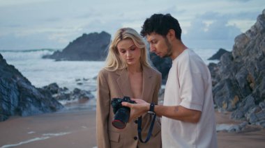 Fotoğrafçı yakın planda model resimleri tartışıyor. Okyanus sahilinde çekim yapan çekim ekibi akşamları kamera görüntülerine bakıyor. Seksi kız müşteri Rocky Coast 'ta çekim yapmaktan zevk alıyor. Yaratıcı hobi