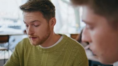 Yeni başlayanlar projeyi yakın planda tartışırlar. Panoramik atölye odasında birbiriyle konuşan iki adam. Genç tasarımcılar hafif yaratıcı ajanslarda iletişim kuruyor.