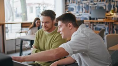 Yaratıcı ekip bilgisayar ekranına yakından bakıyor. Odaklanmış adamlar proje sonuçlarını analiz etmek için birlikte çalışıyorlar. Ciddi akıl hocası girişimci, ofis stajyerini eğitmeye yardım ediyor. İş birliği 