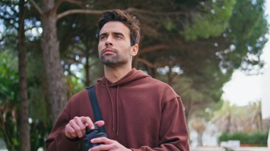 Atletik adam sokakta su içiyor. Yeşil parkta yürüdükten sonra susuz kalan yakışıklı bir koşucu. Latin sporcu plastik spor şişesinden yudumluyor. Sağlıklı şehir yaşam tarzı kavramı.