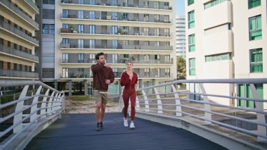 Güneşli bir sabahta şehir köprüsünü yöneten aktif bir çift. Sportif insanlar ayrılık vuruşları hakkında konuşuyor. Spor giyim sektöründe güzel bir kadın şehir caddesinde birlikte koşuyor. Spor sporcuları dışarıda koşuyor..