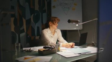 Yorgun bayan gece geç saatlerde ofiste fazla mesai yapıyor. Yorgun iş kadını tek başına çalışarak konsantre olmaya çalışıyor. Kızıl kadın dizüstü bilgisayar kullanıyor. Dolabın çalışma anlarını çözüyor.