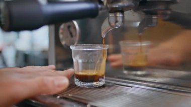 Barmen elleri kafeteryada Americano 'yu modern espresso makinesiyle hazırlıyor. Kahve dükkanındaki profesyonel lezzetli taze içecekler yapıyor. Bilinmeyen kafe çalışanı koyu aromalı kahve dolduruyor. 
