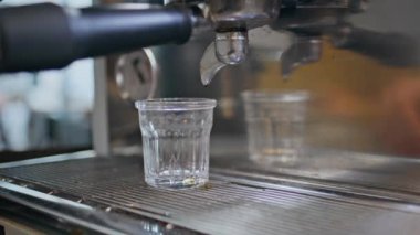 Barmen kafeteryada kahve hazırlıyor. Bilinmeyen garson espresso öğütücü kullanıyor ve aromatik içecek yapıyor. Özel sistem kullanan profesyonel işçiler kafede lezzetli içkiler içiyorlar.