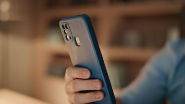 Karanlık ev ofisinde cep telefonu tutan serbest çalışan eller. Ciddi bir iş adamı gece evde akıllı telefon ekranından mesaj okuyor. Cep telefonunda sosyal medyada gezinen yakışıklı adam.