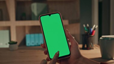 Chroma Key Akıllı Telefon 'da yönetici tarama uygulaması. Akşam ofisi kapanıyor. Kadın serbest çalışan eller evde yeşil ekran cep telefonu çalıyor. Model telefonda internette sörf yapan tanınmamış bir iş kadını..