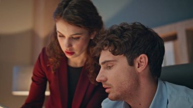 Kadın asistan, akşam ofisindeki erkek çalışana tablet verilerini gösteriyor. İş yerinde proje bilgilerini tartışan iki ciddi meslektaş. Takım çalışması verimlilik kavramı.