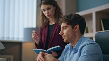 İş adamı, şirket ofisinde birlikte çalışan kadın asistanla konuşuyor. Yakın çekim. Odaklanmış kadın sekreter notlar alıp dinliyor patron. İki iş arkadaşı sabah toplantılarında günlük işleri tartışıyor..