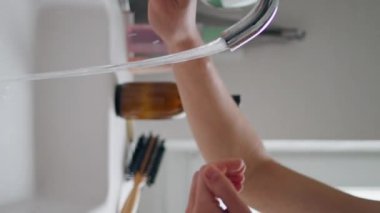 Bir kadın evdeki musluğu dikey olarak yıkıyor. Seramik lavabosuna akan soğuk su. Bilinmeyen kadın lavabo kullanıyor. Hafif dairede kollarını temizleyen genç bayan. Hijyen kavramı