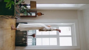 Gergin bir kadın dikey odada pencereyi izliyor. Gecelikli rahat kız güne ev içinde başladı. Sakin bir bayan yalnız başına rahat bir dairede tembel bir hafta sonunun tadını çıkarıyor. Yurt içi yaşam tarzı