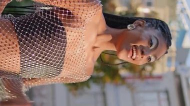 Summer City 'de el sallayan heyecanlı bir kadın dikey çekimde arkadaşını selamlıyor. Şehir merkezinde erkek arkadaşıyla buluşan neşeli bir bayan. Gülümseyen Afro-Amerikan modeli merhaba diyor. Şehre bakıyorum.