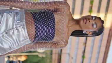 Şık esmer model, dikey olarak tek başına geziniyor. Muhteşem Afrikalı kadın fotoğraf makinesinde poz veriyor. Moda dünyasındaki rahat kız yaz yürüyüşünün tadını çıkarıyor. Moda insanları
