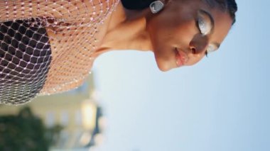 Rahatlamış bir bayan yaz manzarasını seyrediyor. Gözler kapalı ve zevkli dikey video çekimleri var. Afro-amerikan modayla ilgilenen kameralar kentsel yol portresi çekiyor. Güneşli şehirde poz veren modaya uygun bir kadın.