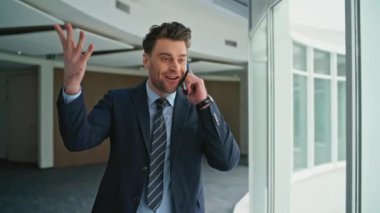 Koridordaki pencerelerde yürüyen mutlu yönetmen konuşuyor. Heyecanlı bir yönetici telefon konuşmasından keyif aldığını ve belgeleri attığını ifade ediyor. Kendine güvenen işadamı cep telefonuyla harika haberler paylaşıyor..
