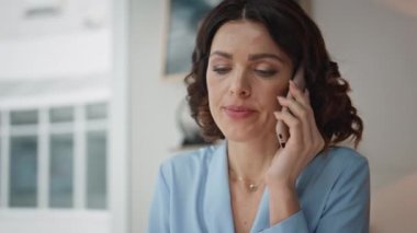 Patroniçe, akıllı telefondan şirket odasında mali raporları tartışıyor. Ciddi bir iş kadını. Evrakları analiz ediyor. Ofisteki ortakları arıyor. Endişeli kadın telefonda konuşuyor..