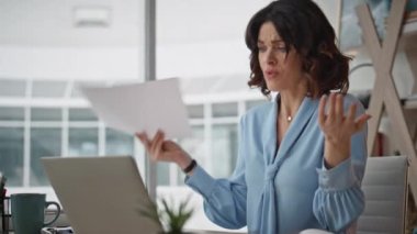 Patron, iş yerinde bilgisayarın kapağını kapatma toplantısından memnun değil. Gergin iş kadını ofiste elinde kağıtlarla görüntülü aramayı bitirdi. Web konferansından sonra duygusal yürütme hissi.