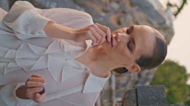 Eski bina merdivenlerinde böğürtlen kokusundan hoşlanan romantik bir kadın. Rahatlamış kız parmaklarında dikey çekimde aromatik vitamin böğürtlenini kokluyor. Sakin model bir avuç organik böğürtlen