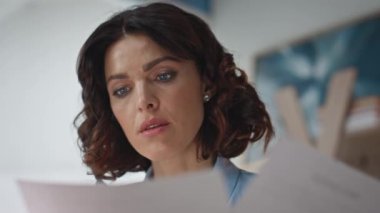 Evrakları inceleyen düşünceli muhasebeci sıkıntılı bir kapanış yaşıyor. Endişeli iş kadını memnuniyetsiz mali rapor. Ciddi girişimci hayal kırıklığına uğramış ifadeyle belgeleri okuyor