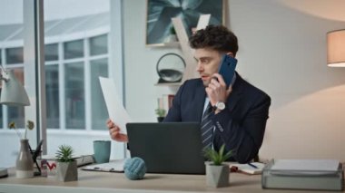 Ofisteki belgeleri okuyan iş adamını aramak, yakın çekim hissi uyandırıyor. Yönetici, iş yerinde konuşan akıllı telefonlardan notlar alıyor. Profesyonel telefon iletişimi ile ilgileniyor. İş belgelerini inceliyor.