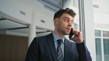 Girişimci cep telefonu konuşmalarında çalışırken ofis penceresinden yakından bakıyor. Ciddi bir iş adamı akıllı telefonları ayakta duran koridorda arıyor. Profesyonel erkek, telefon iletişiminde..