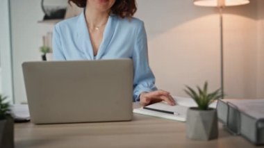 Profesyonel bir kadın laptopuyla masa başında notlar yazıyor. İş kadını, modern ofis çalışma alanındaki fikirlerini not alıyor. Ajans işyerindeki işlerle ilgilenen kadın şirket çalışanı.