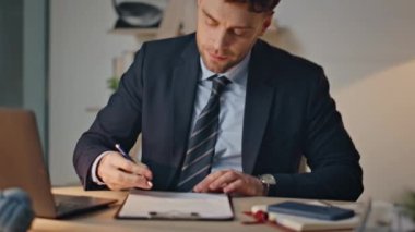 Masa başında kağıt yazan gülümseyen bir işadamı. Şirket yöneticisi evrak işleriyle uğraşıyor akşamları. Şirket işyerindeki iş yerine odaklanan profesyonel yönetici.