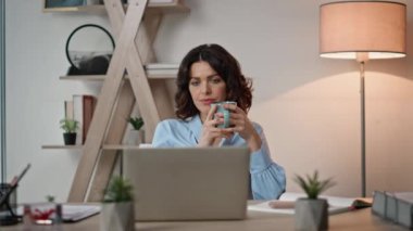Şirket CEO 'su modern ofiste kahve içiyor. Masada dizüstü bilgisayara bakan düşünceli bir iş kadını. Ciddi bir girişimci kadın. İş geliştirme konusunda düşünce sandalyesinde dinleniyor..