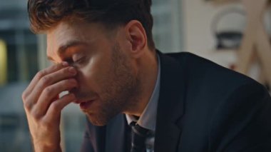 Bunalmış iş adamı, gece geç saatlerde ofiste çalışırken stres hissediyor. İş yerinde baş ağrısı çeken bitkin bir şirket yöneticisi gözlerini kapatıyor. Girişimci endişeli iş sorunu.