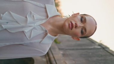 Tasasız bayan, eski taş binada akşam yürüyüşü yapıyor. Terk edilmiş eski mimariyi haftasonu dikey görüntüsünde tek başına keşfeden genç bir kadın. Güzel kız eski şatonun yakınlarında gezinen kameraya bakıyor.