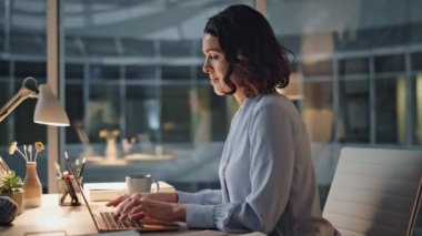 Gülümseyen sekreter akşam ofis masasında dizüstü bilgisayarda daktilo raporunu hazırlıyor. Profesyonel yönetici, iş yerinde bilgisayar kapağı kapağı projesini bitiriyor. Kadın şirket çalışanı iş gününden memnun.