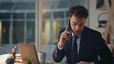 Endişeli iş adamı akşam ofisindeki akıllı telefondan konuşuyor. İletişim hoşnutsuz. Şirket yöneticisi iş yerindeki telefon konuşmalarından memnun değil. Ciddi çalışan geç saatlere kadar çalışıyor..