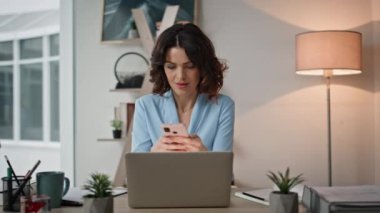Dizüstü bilgisayarda çalışan akıllı telefona benzeyen bir bayan. Mutlu bayan girişimci ofisteki cep telefonundan harika haberler alıyor. Heyecanlı iş kadını cep telefonundan banka bildirimi okuyor..