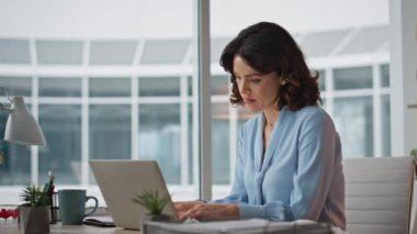 Modern ofiste evrak okumakla meşgul bir iş kadını kendini yorgun hissediyor. Odaklanmış kadın yönetici bilgisayarda kağıtları kontrol ediyor. Bulanık çalışan planlaması proje raporları çalışma yerinde okunuyor.