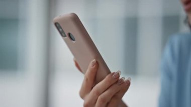 Akıllı telefonu yakın plan çeken bir kadın. Ofis ortamında cep telefonu ekranı okuyan çekici bir iş kadını. İş yerinde cep telefonuyla sosyal medyayı izleyen rahat bir bayan..