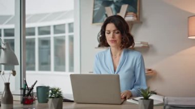 Ofiste evrak işlerine odaklanan özenli bir kadın. Yakın plan. Ciddi bir iş kadını laptop masasında çalışırken anlaşma yapmayı düşünüyor. Çağdaş işyerindeki iş görevlerini çözmekle meşgul kadın yönetici.