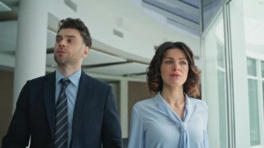 Ofis koridorunda kendine güvenen iş ortakları var. Şık takım elbiseli başarılı bir iş adamı şık bir iş kadınıyla şirket konferansına gidiyor. Şirket toplantısı için acele eden iki yönetici..