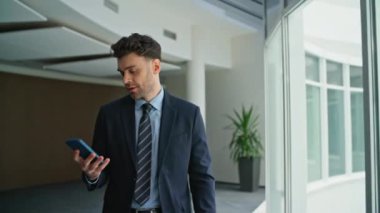 Patron panoramik pencerelerin yakınındaki şirket ofisinden çağrıya cevap veriyor. Şirket koridorunda gülümseyen profesyonel bir yönetici akıllı telefondan konuşuyor. Güvenilir yöneticinin dost canlısı cep telefonu konuşması var.