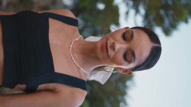 Dikey yakın plan zarif esmer yaşlı taş köprünün yanında dikiliyor. Yaz akşamında poz veren genç bir kadının portresi. Muhteşem modaya uygun model dışarıda dinleniyor ve hafta sonunun tadını çıkarıyor..