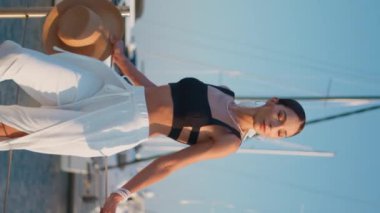 Hayalperest kadın, iskele yaz akşamında elinde saman şapkayla dinleniyor. Lüks beyaz yatların önünde şık kıyafetler içinde poz veren muhteşem bir kadın. Kaygısız kız okyanus kıyısında tek başına duruyor.