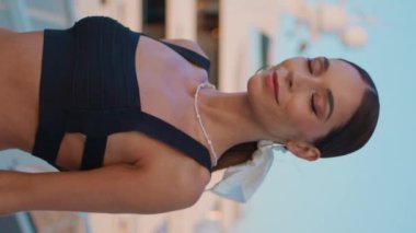 Güzel esmer, yürüyen iskelede kaygısız deniz tatili, dikey meleğin yakın çekimi. Lüks yatın yakınındaki sette gezinen zarif gülüşlü modaya uygun bir kadın. Muhteşem mutlu kız yalnız başına rahatlıyor.