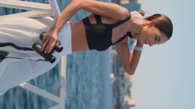 Yaz dikey videosunda dürbünle deniz manzarası izleyen bir bayan. Okyanus manzarasına bakan zarif, kaygısız bir kadın güneşli sette duruyor. Muhteşem dişi gezgin Akdeniz manzarasının tadını çıkarıyor..