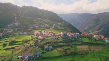 Yeşil teraslı tepelerdeki insansız hava aracı manzaralı dağ köyü. Panorama sahalarında kırmızı kiremitli binalar olan güzel bir kırsal bölge. Madeira Adası 'ndaki bulutlu gökyüzü altında sakin bir kırsal bölge.