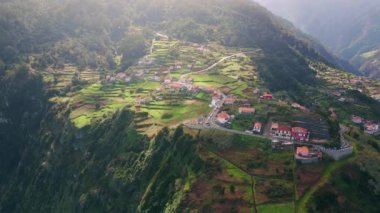 Teraslı dağ köyü, güneş ışığı drone manzaralı. Madeira Portekiz 'in yeşil alanlarındaki kırsal kesim. Geleneksel kırmızı kiremitli mimari ile resim gibi sakin bir manzara. Sakin kasaba panoraması.