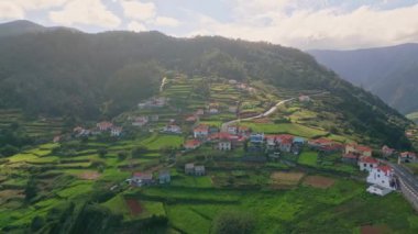 Kırmızı çatıları olan geleneksel insansız hava aracı binaları köyü. Madeira 'daki yemyeşil arazi manzarası. Dağlardaki sakin kırsal kesimin havadan görünüşü. Güzel seyahat konsepti.