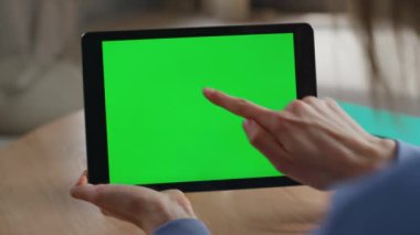 Çevrimiçi Chroma Key Tablet 'ten alışveriş yapan kız apartman dairesi kapanışı. Kimliği belirsiz bir kadın evde yeşil ekranlı bilgisayara dokunuyor. İş kadını dijital aygıtta banka uygulamasına göz atıyor.